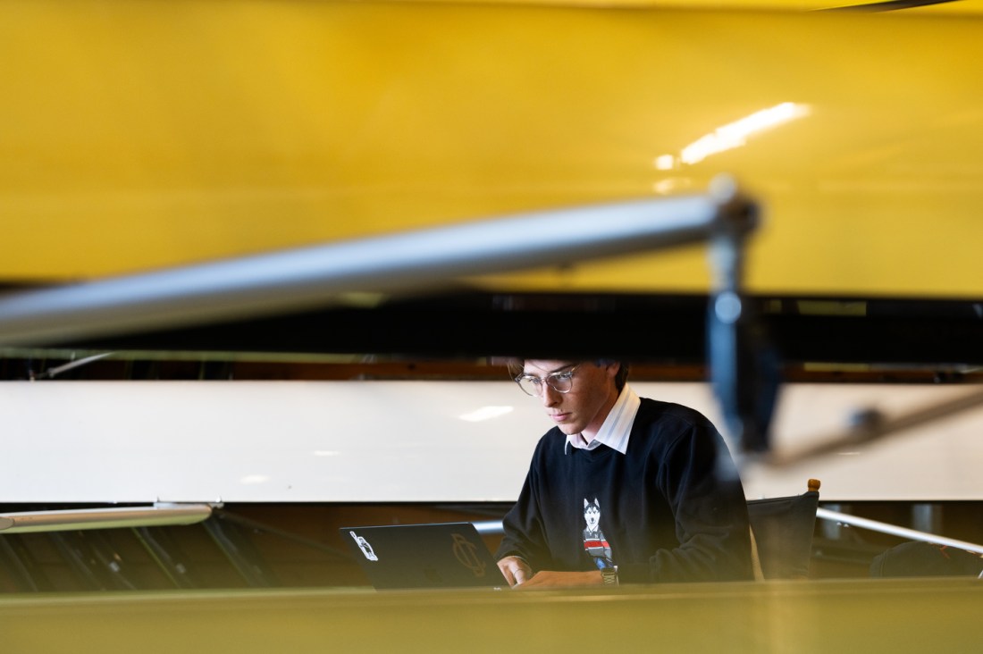 Northeastern University student Nick Walding works on his laptop in the Northeastern boat hosue
