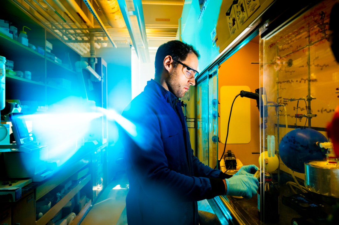 Markos-Orestis Georgiadis, wearing a lab coat and goggles, stands at a lab station which has balloons, a heat gun and other equipment. He manipulates some of the equipment.