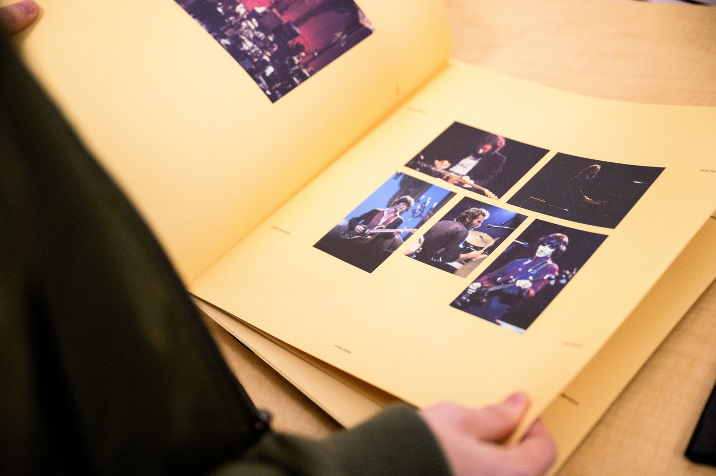 A hand flipping through a book of photos of a band performing on stage. 