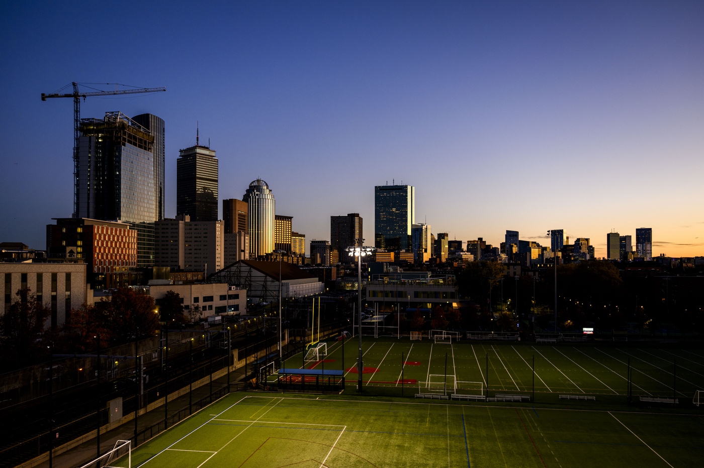A view of Carter Field with the Boston skyline in the background at dusk. 