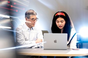 Lei Xie and You Wu sitting side by side looking at a laptop.