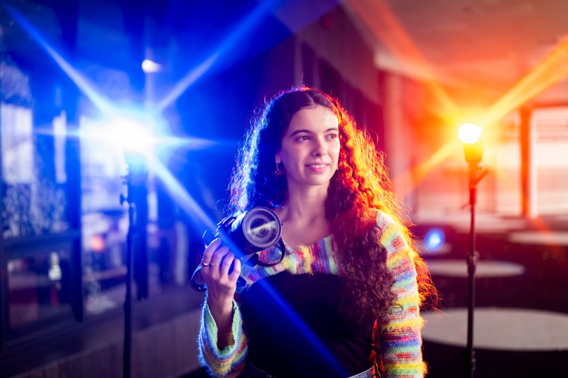Samantha Davidson poses for a portrait while holding a camera.
