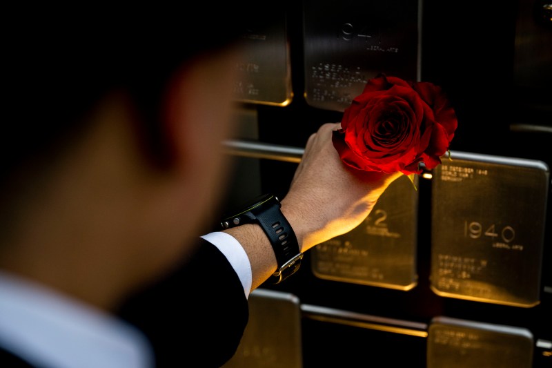A person places a red rose on a name plaque on the Northeastern Veterans memorial. 