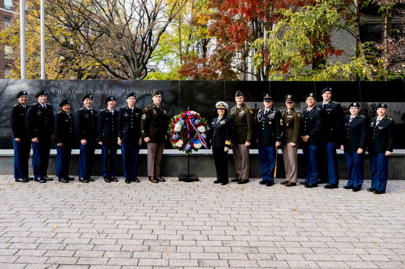 A group of people posing in front of the Northeastern Veterans Memorial. 