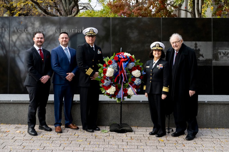 A group of people posing in front of the Northeastern Veterans Memorial. 
