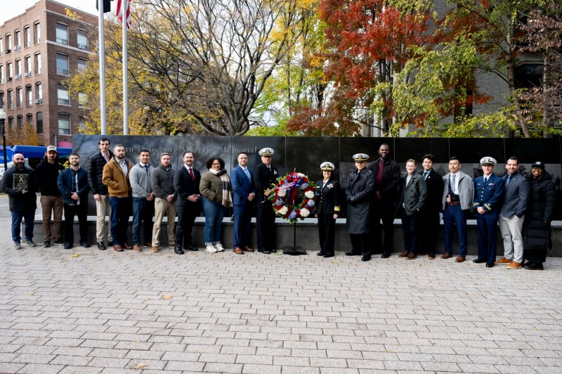 A group of people posing in front of the Northeastern Veterans Memorial. 