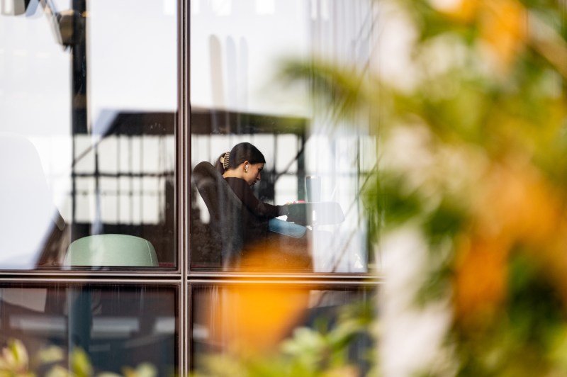 A member of the Northeastern community sits by glass windows in ISEC.