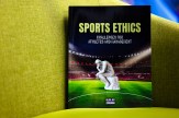 The cover of Sports Ethics, by Alan Zaremba. The book has a picture of Rodin&#039;s sculpture &quot;The Thinker&quot; on a stadium field. The book itself rests on a yellow couch.