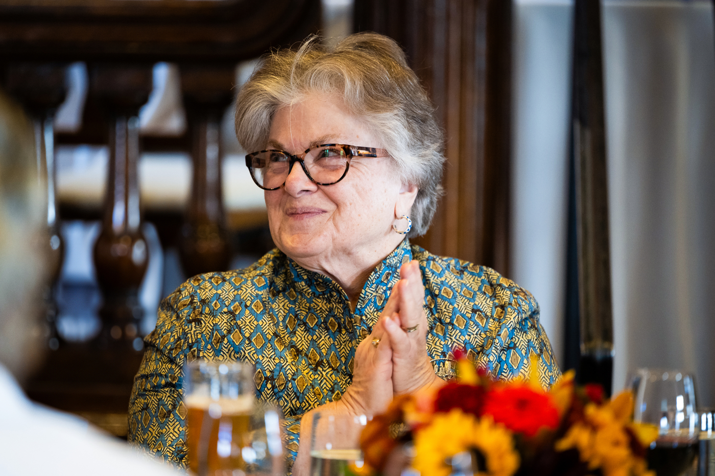 Deanna Jantzen smiles and claps her hands while listening to a speaker at a luncheon celebrating her 50 years at Northeastern University.