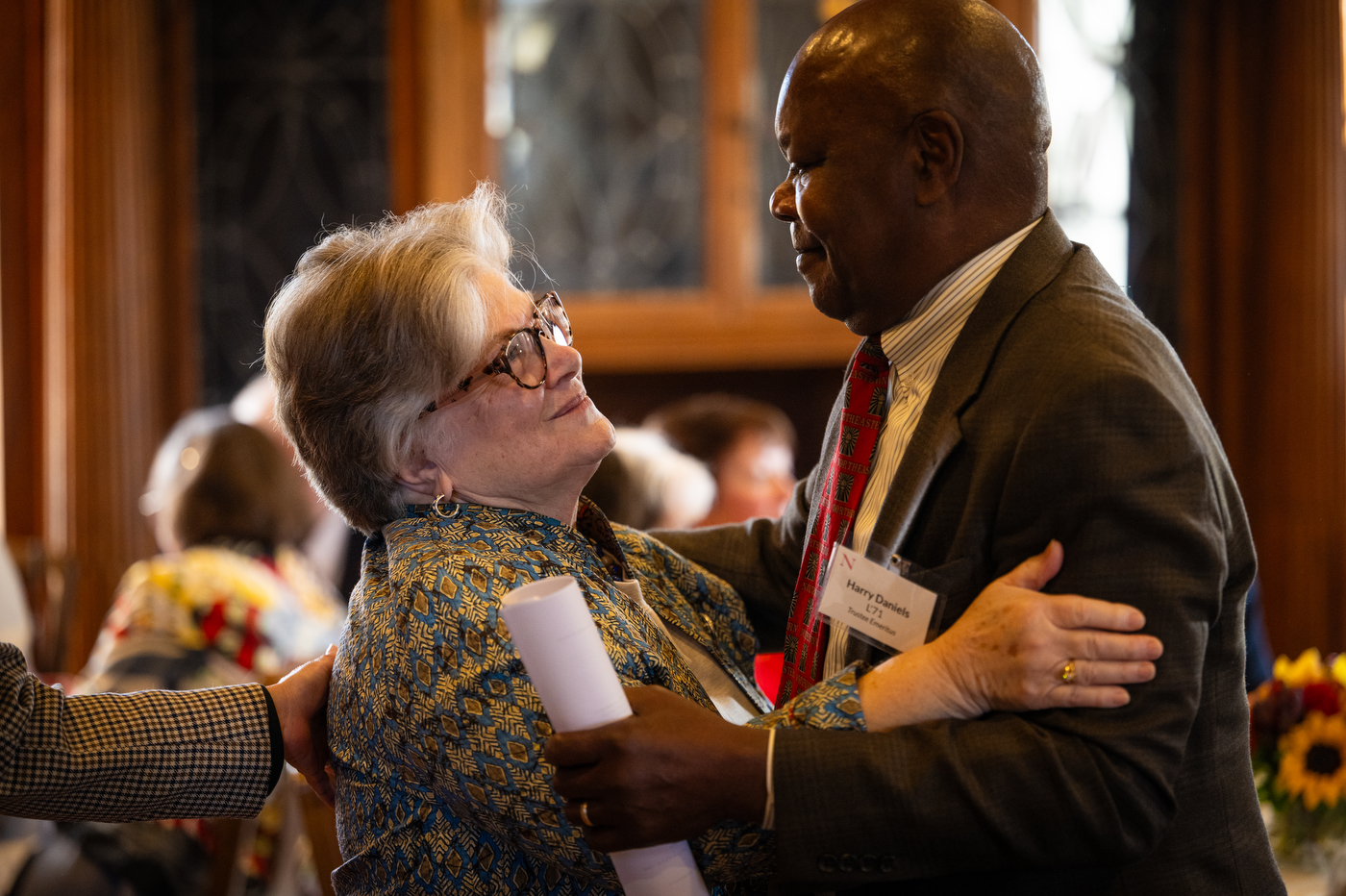 Deanna Jantzen hugs a bald man with a red tie at the luncheon event at the Endicott Estate.