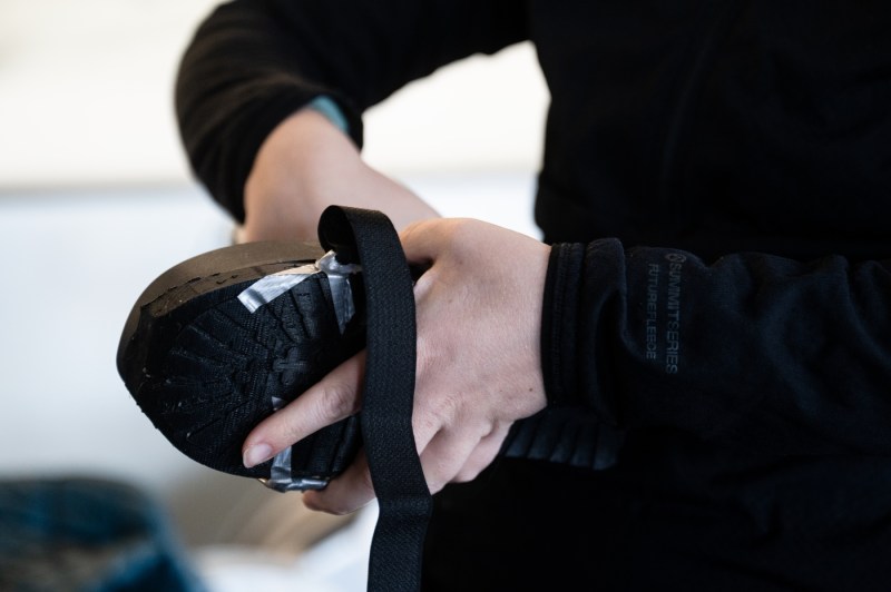 Close-up of hands holding a rowing oar handle with the blade visible, showing the connection between the shaft and blade.