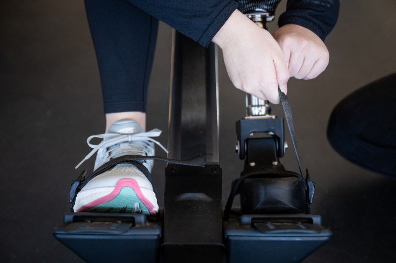 Close-up of a prosthetic leg attached to a rowing ergometer footplate, showing the connection between the prosthetic and rowing equipment.