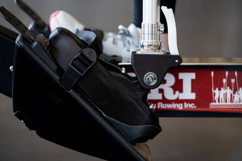 Close-up of adaptive rowing equipment showing a specialized seat or mounting system with straps and metal hardware.