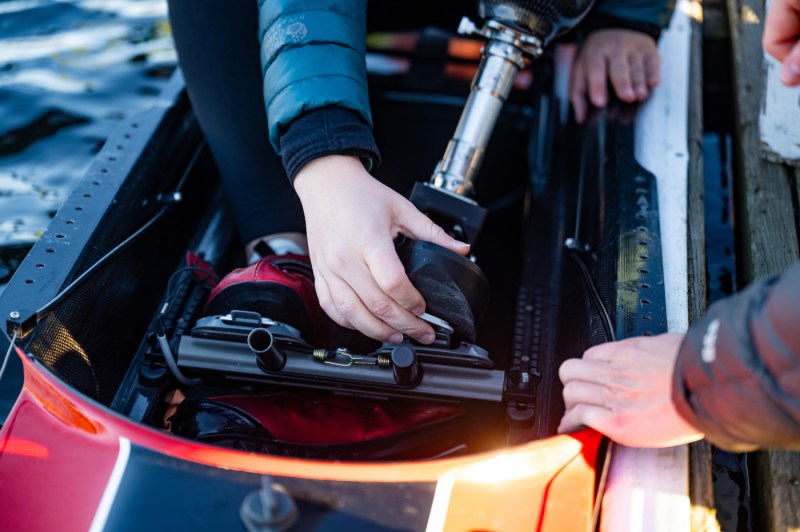 Megan Hopkins, a para-athlete, clips in the prosthetic foot and ankle designed specifically for rowing by Northeastern bioengineering undergraduate students, before testing it on the Charles River on Tuesday, Nov. 18, 2025.