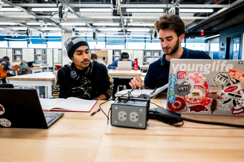 Two people do electrical work at a workbench in the Makerspace.
