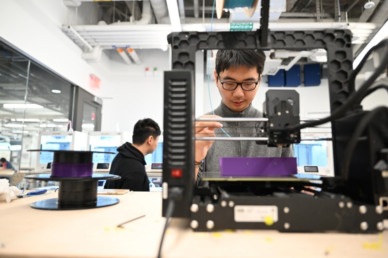 A student does electrical work at a workbench in the Makerspace.