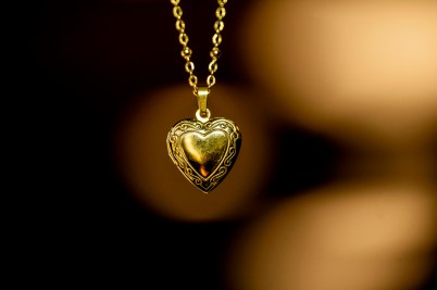 A gold-tone heart-shaped locket hangs on a gold-tone chain.