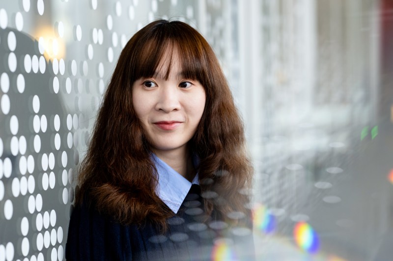 Headshot of Chenyan Jia, who poses in front of a wall designed with circles on it.