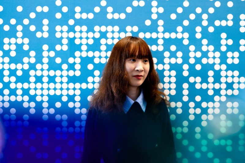Headshot of Chenyan Jia, who poses in front of a wall designed with circles on it.