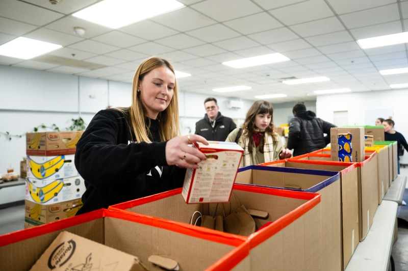 People pack cardboard boxes full of food.