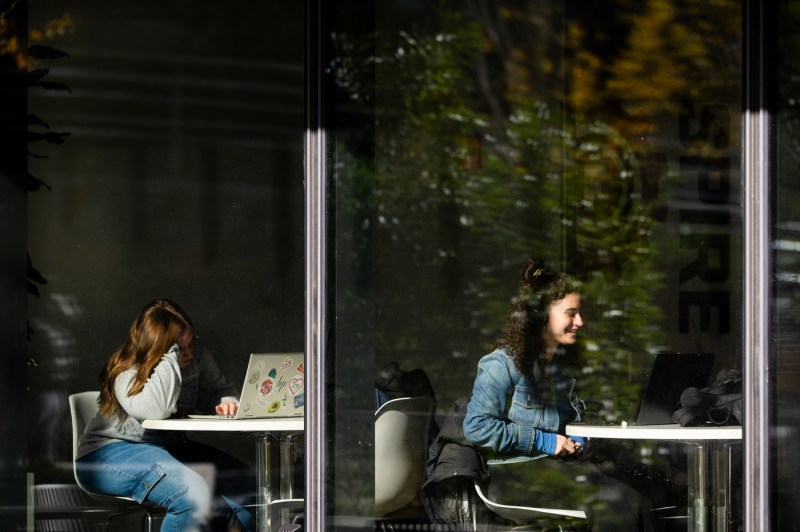 Photographed through the glass windows, students sit at tables in ISEC. 