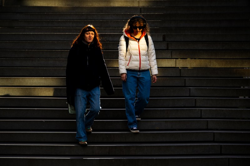 Two members of the Northeastern community walk down a set of stairs outside. 
