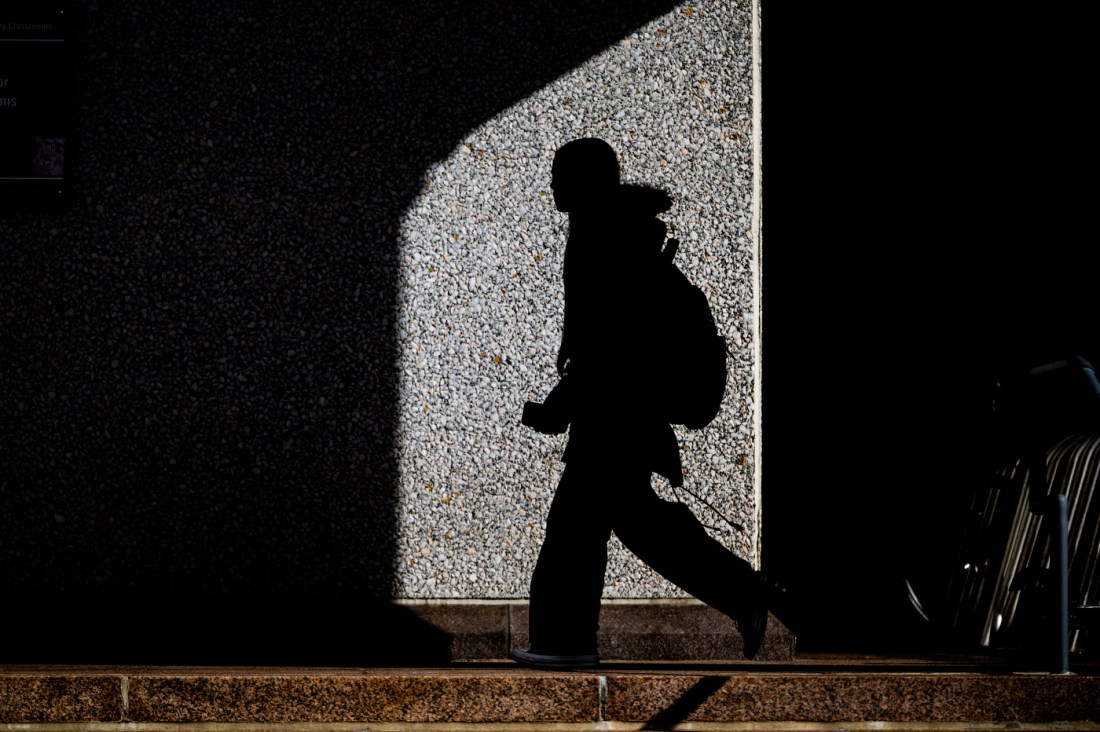 A silhouette of a person walking through the Boston campus.