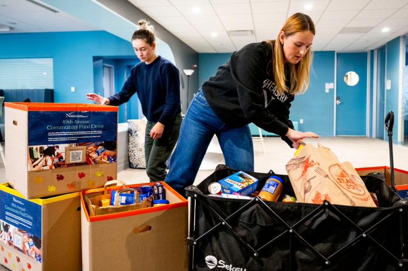 Two people organize cardboard boxes for a food drive.