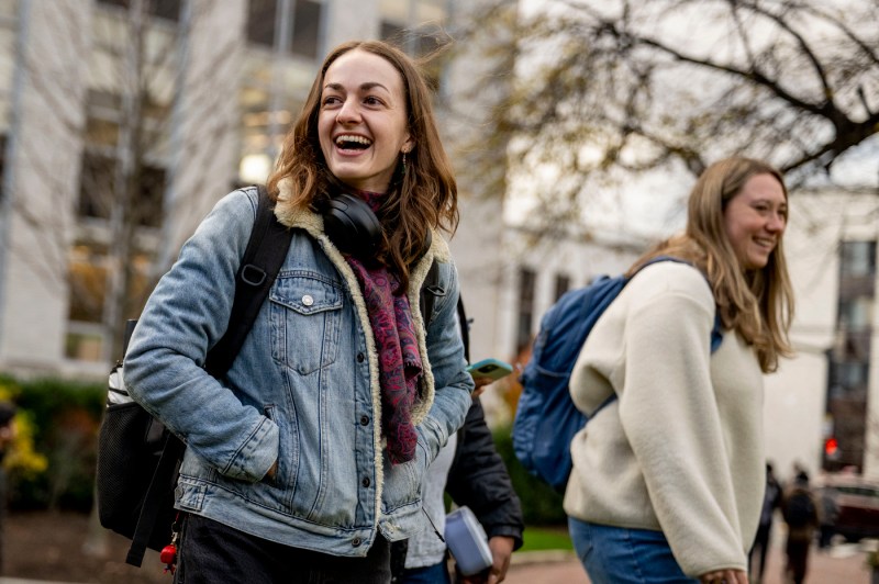 Two students with backpacks smile while outside for class.