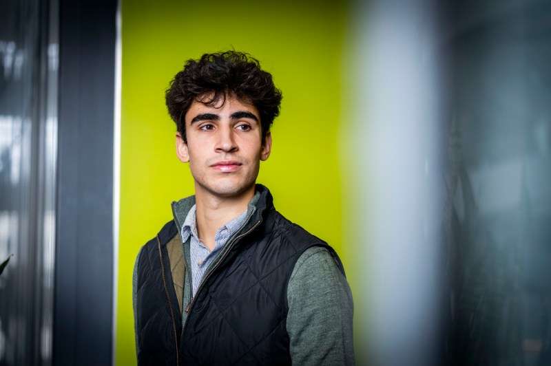 A person poses for a portrait in front of a lime green wall.