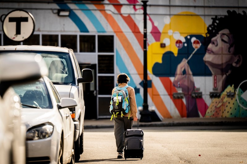 A student wheels a suitcase toward Ruggles station.