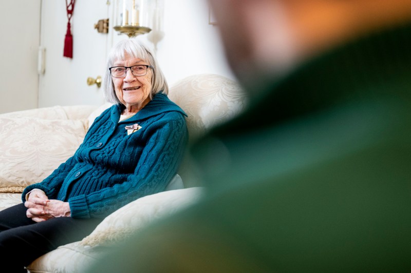 Ruth Gove sits on a sofa in her room as she speaks with a journalist.