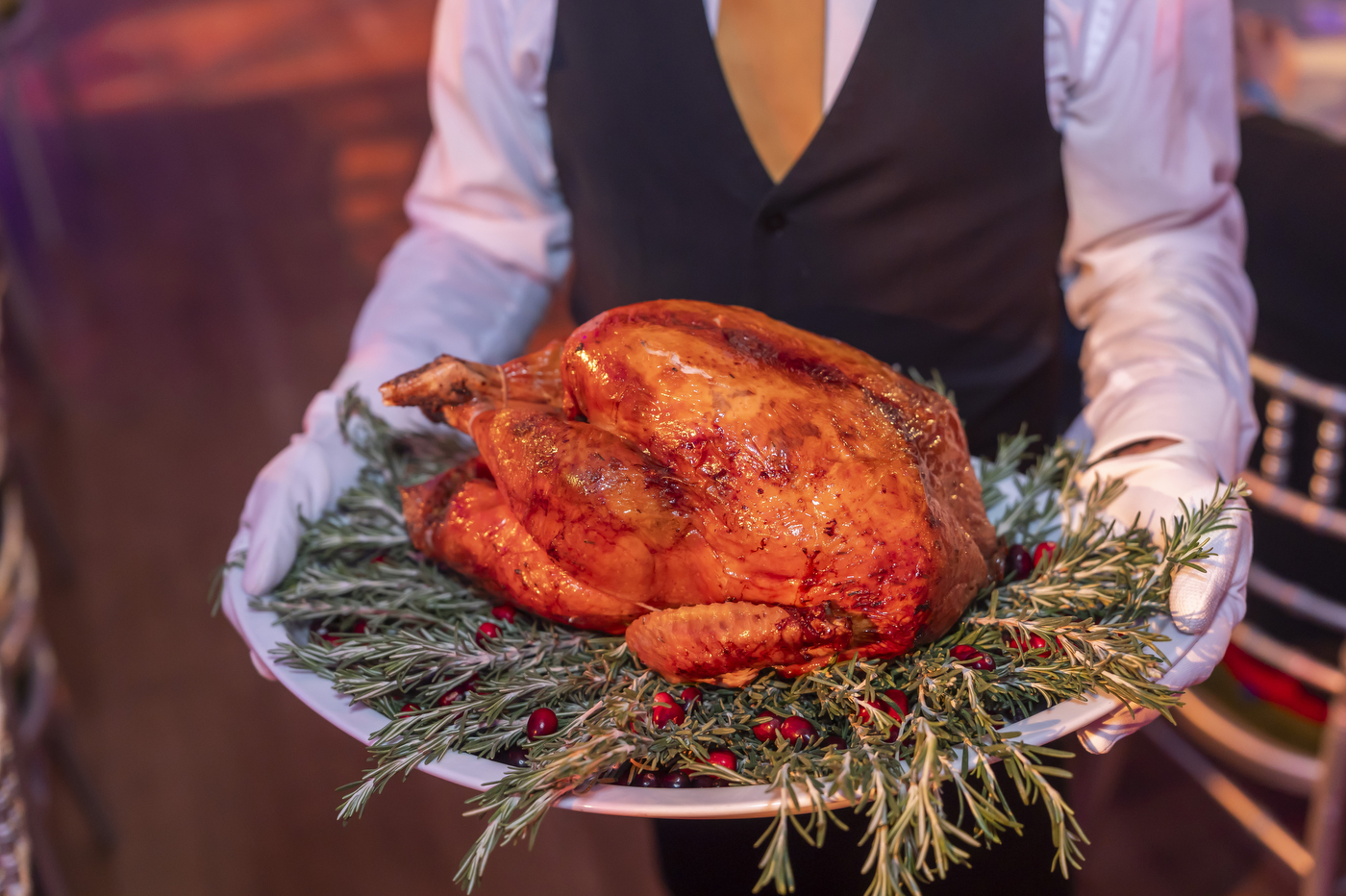 A cooked turkey on a platter with rosemary garnish