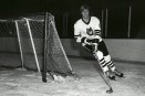 A black and white photo of David Sherlock on the ice, skating around the goal