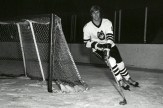 A black and white photo of David Sherlock on the ice, skating around the goal