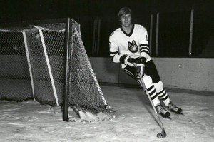 A black and white photo of David Sherlock on the ice, skating around the goal