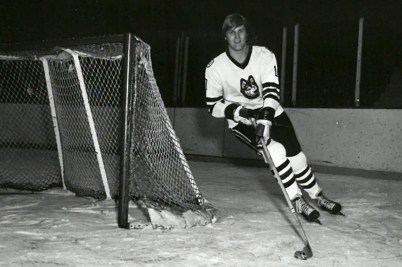 A black and white photo of David Sherlock on the ice, skating around the goal
