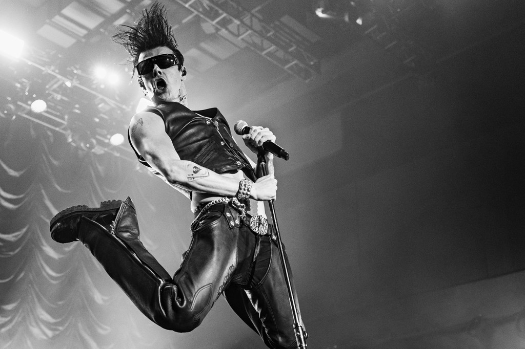 British rocker Yungblud, donned in black leather, leaping in the air during a concert.