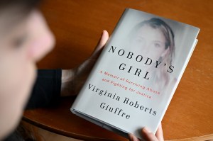 A person holds a white-covered book titled Nobody’s Girl: A Memoir of Surviving Abuse and Fighting for Justice.