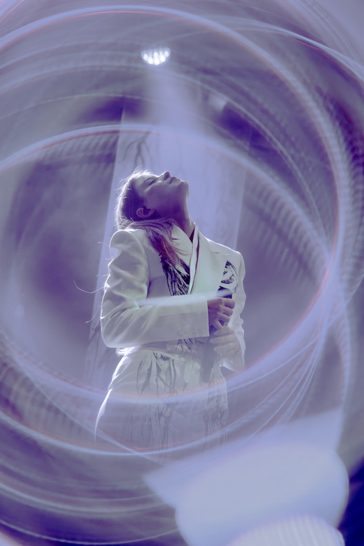 Stage photo featuring British artist Paris Paloma, her head lifted toward the sky.