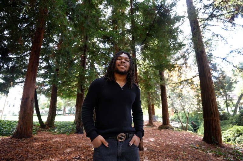 Tony Galloway is standing outdoors with his hands in his pockets and smiling.