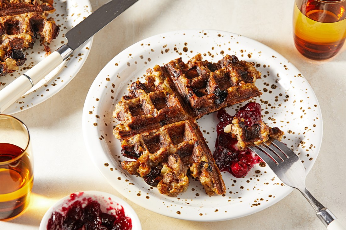 A closeup of a waffle made out of leftovers on a plate cut into quarters.