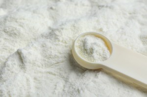 A scoop of baby formula in the form of a white powdery substance.