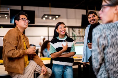 A group of people stand in a circle smiling and holding drinks in their hands