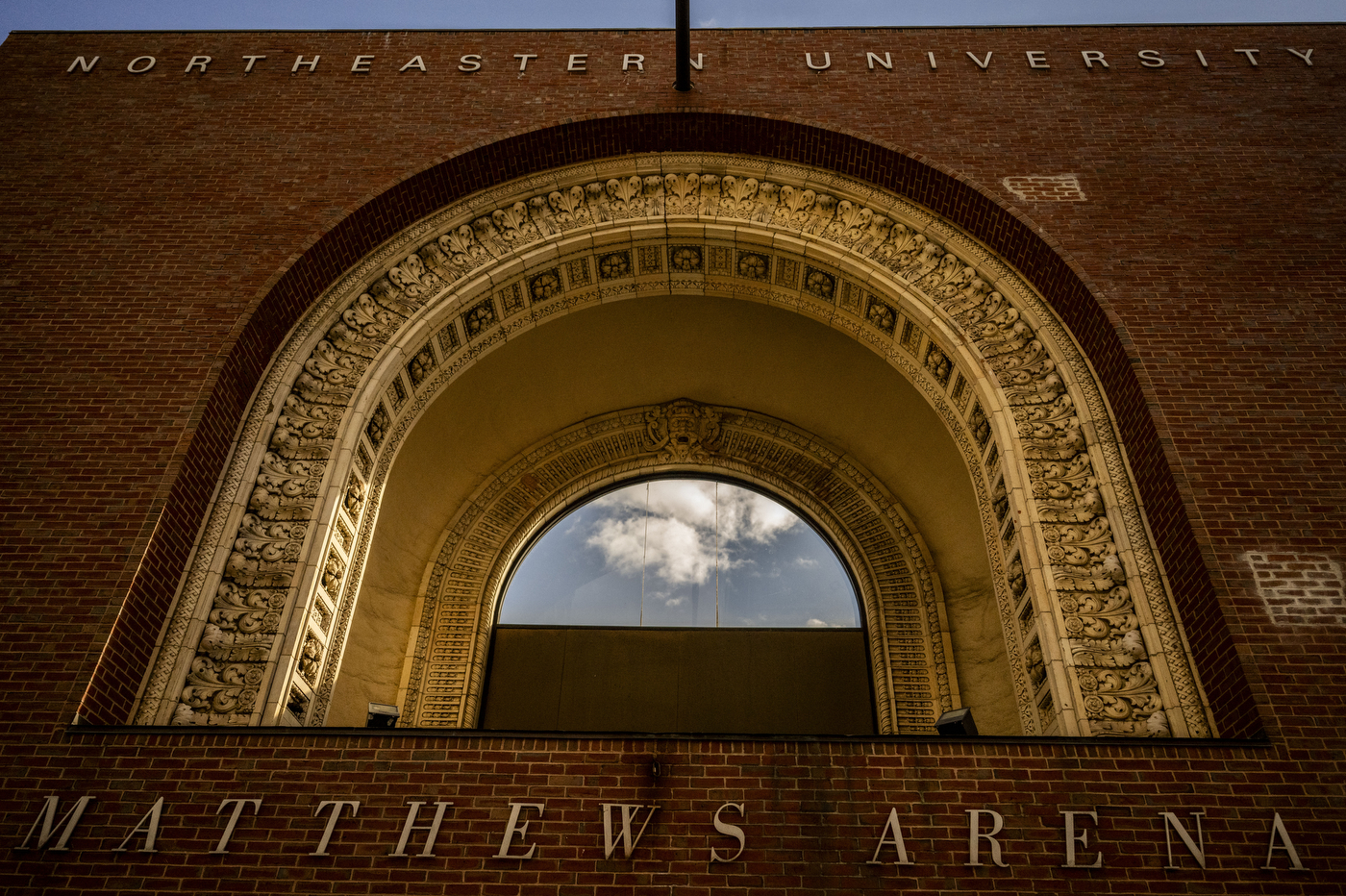 An ornate terra cotta archway entrance to Matthews Arena with Northeastern University lettering above. 
