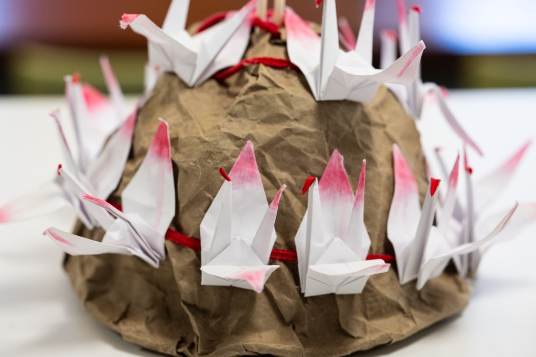 A sculptural artwork made from brown paper and white folded paper shapes sits on display, resembling a textured mound with protruding forms.