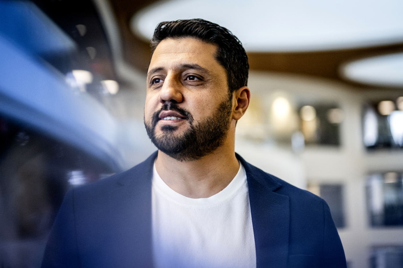 A headshot of a person wearing a white shirt with a blue blazer. 