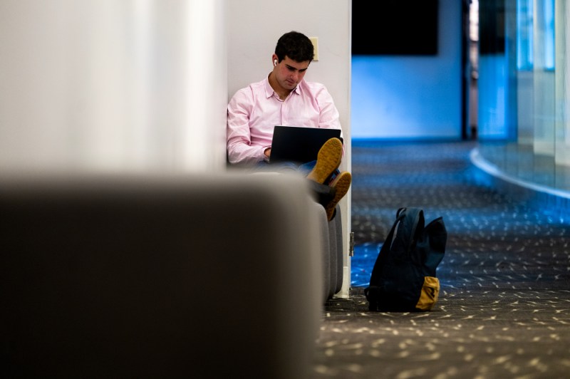A student sitting with their legs up works on a laptop. 