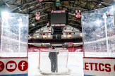 A person stands in front of a hockey net on the ice at Matthews Arena.