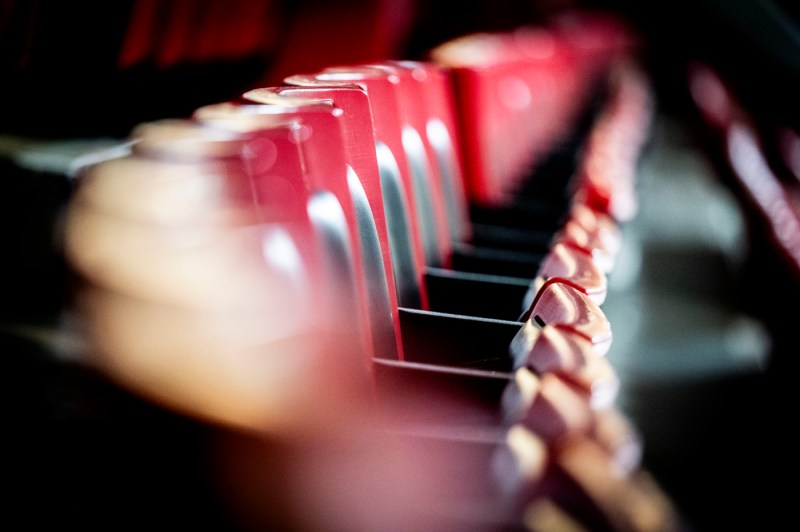 Artistic motion-blurred photograph of red stadium seats arranged in a row, creating an abstract effect with soft focus and movement.